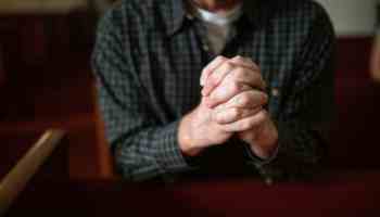a person in blue and black long sleeve shirt praying