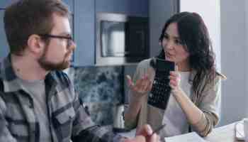 woman sitting at table holding a calculator