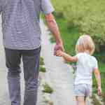 man and child walking near bushes during daytime